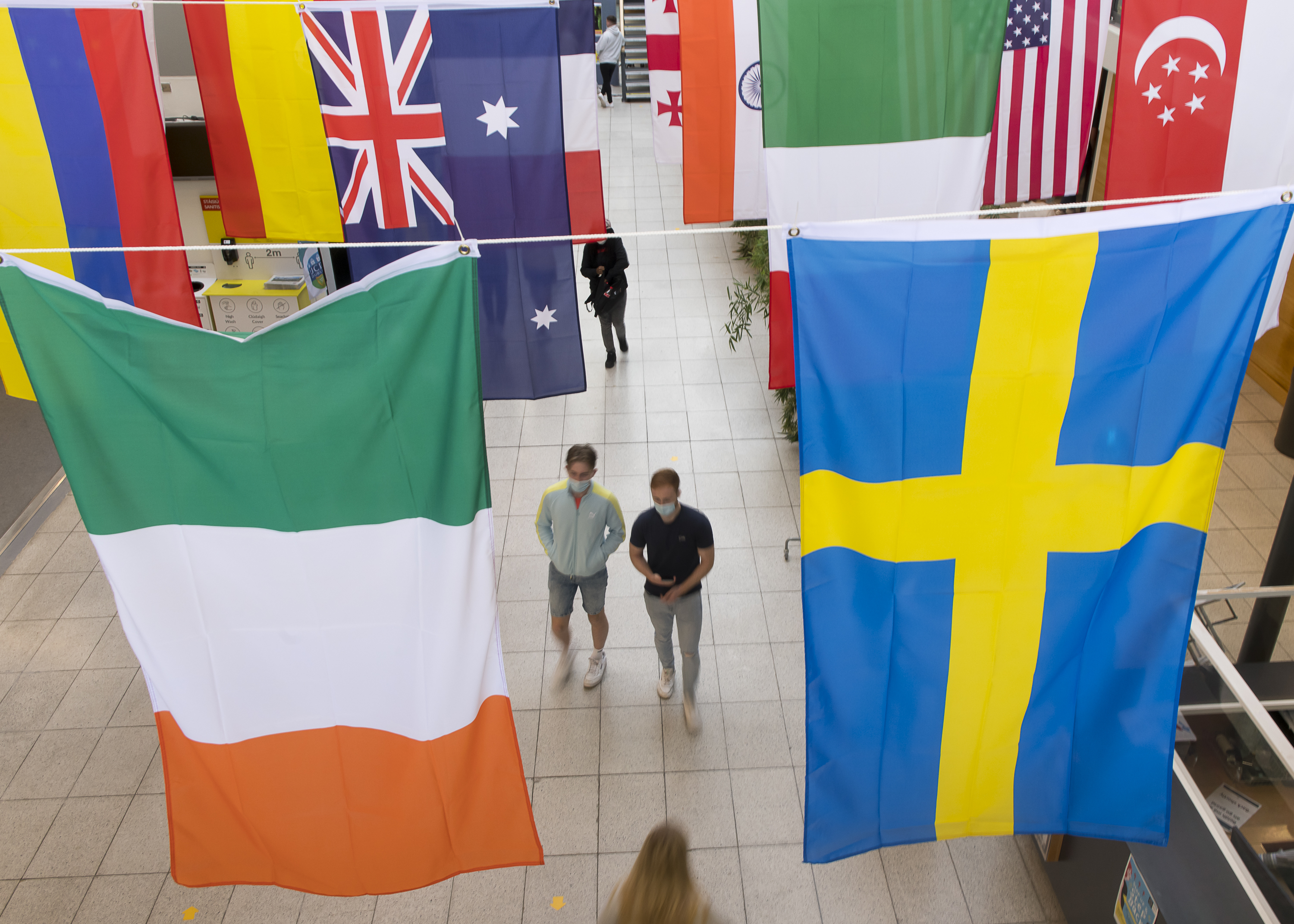 Two students looking at the photographer, with large flags hanging above them