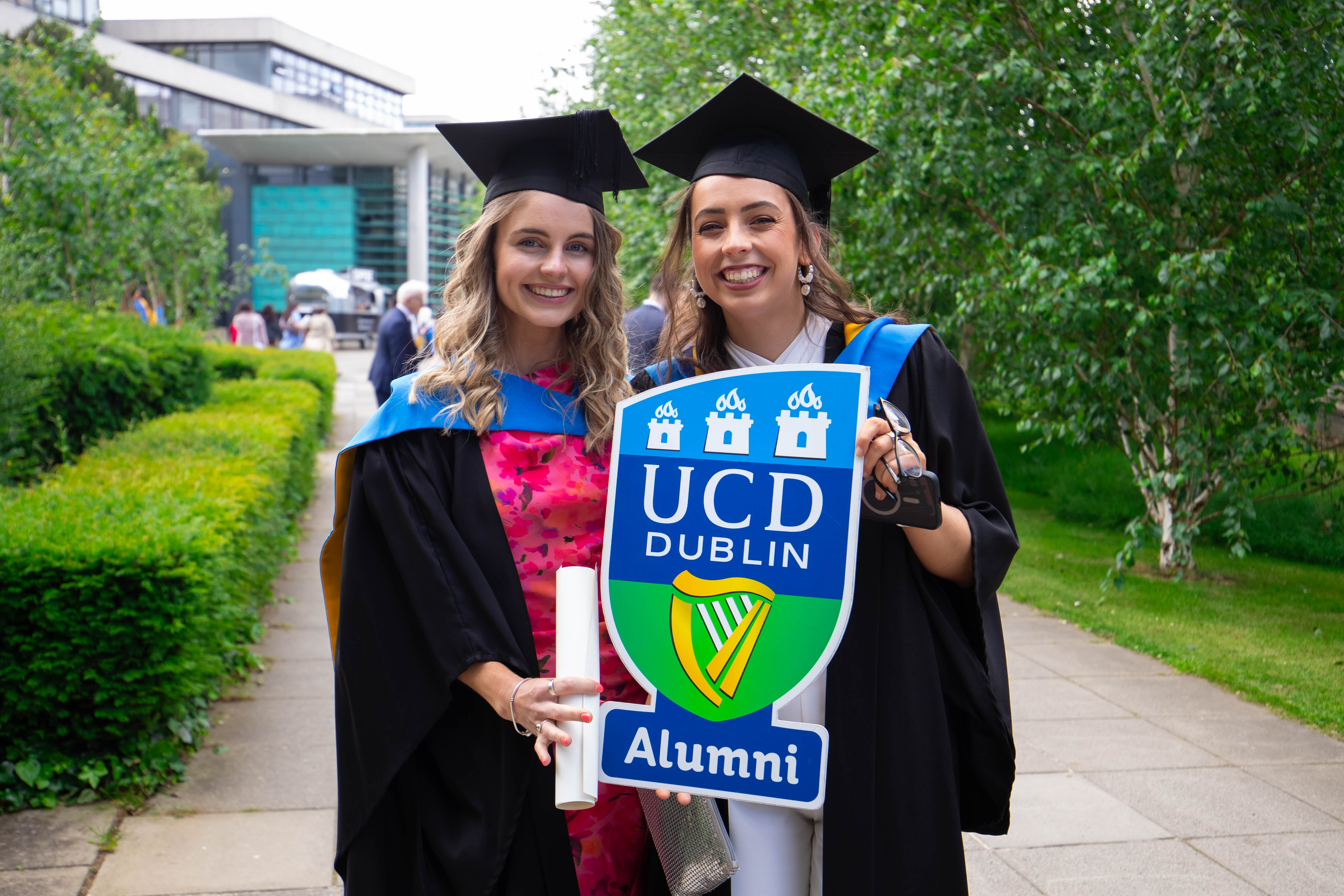 2 students holding alumni sign