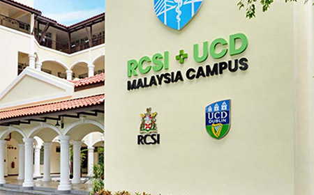 A pale coloured building with the RSCI and UCD logo on the front.