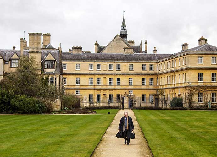 Large, yellow building with a groomed green lawn in the forefront.