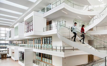 Students walking down white stairs in a large building.