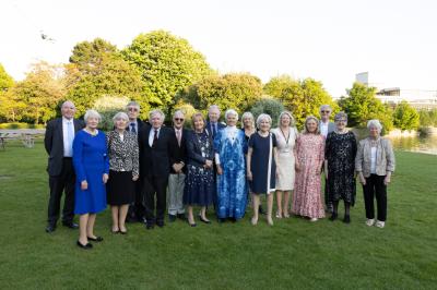 The Medicine class of 1975 standing on grass in front of lake