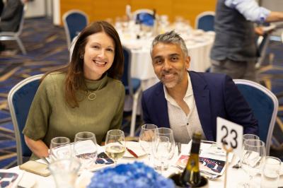 A woman and a man sat at a table at the MGA Gala Dinner smiling at the camera