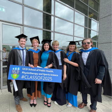 UCD graduates in caps and gowns holding a sign saying Class of 2025