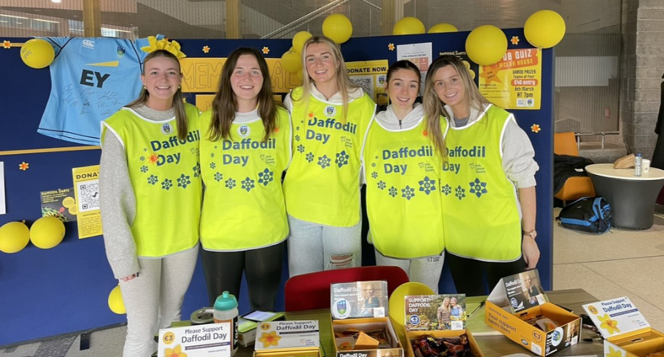Group of students in yellow high vis bibs saying Daffodil Day
