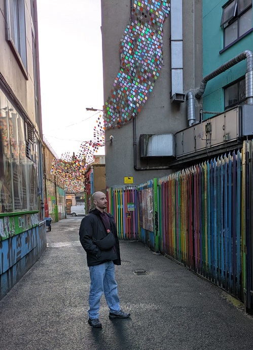 Man standing by colourful art display outdoors