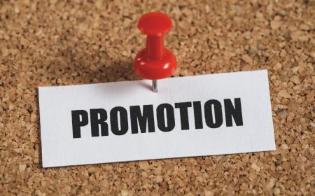 A sticky note with the word promotion on a cork board